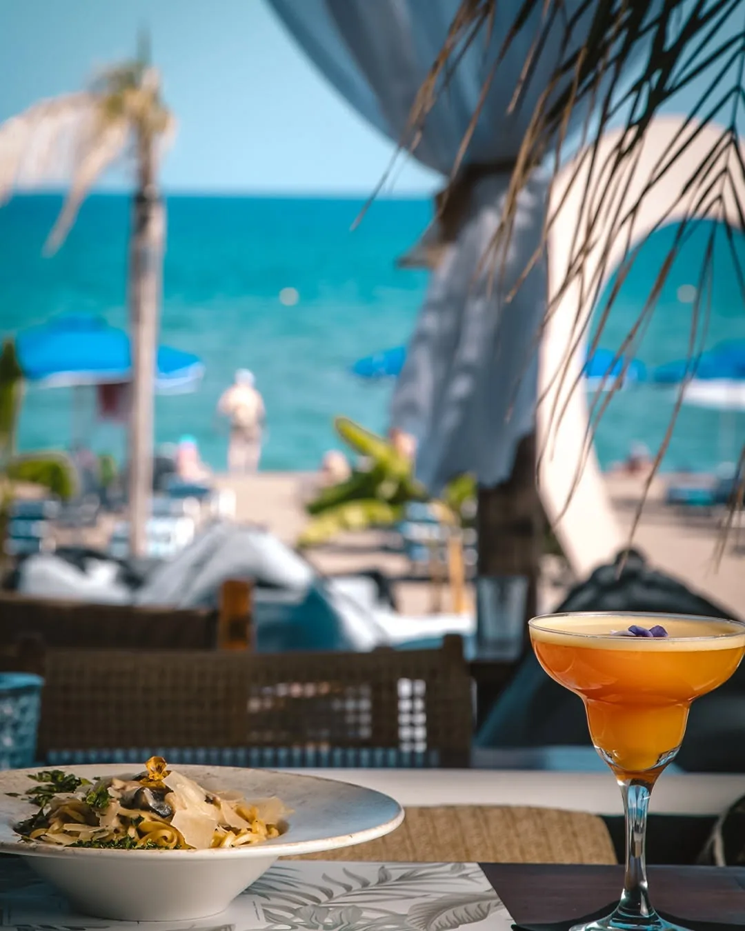 Cocktail του Exótico σε τραπέζι με θέα στη θάλασσα και τις ξαπλώστρες του beach bar